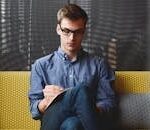 Person in Blue Denim Jacket Sitting on Chair While Writing